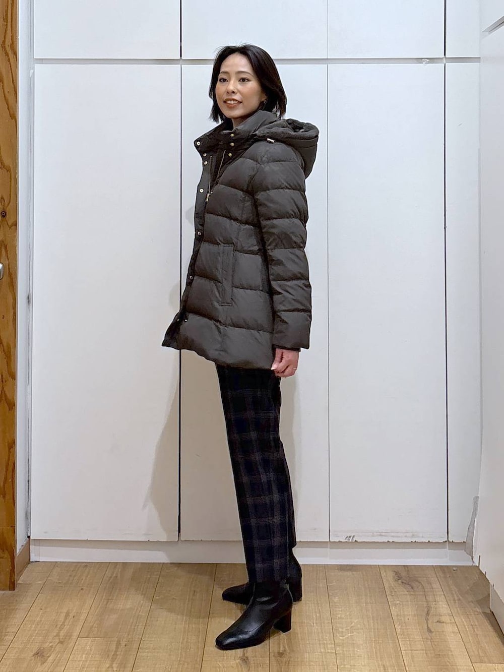 ブラウン系のダウンジャケット/コート、ブラック系のニット/セーター、ブルー系のその他パンツを着用したレディースの秋コーディネートの2枚目の写真