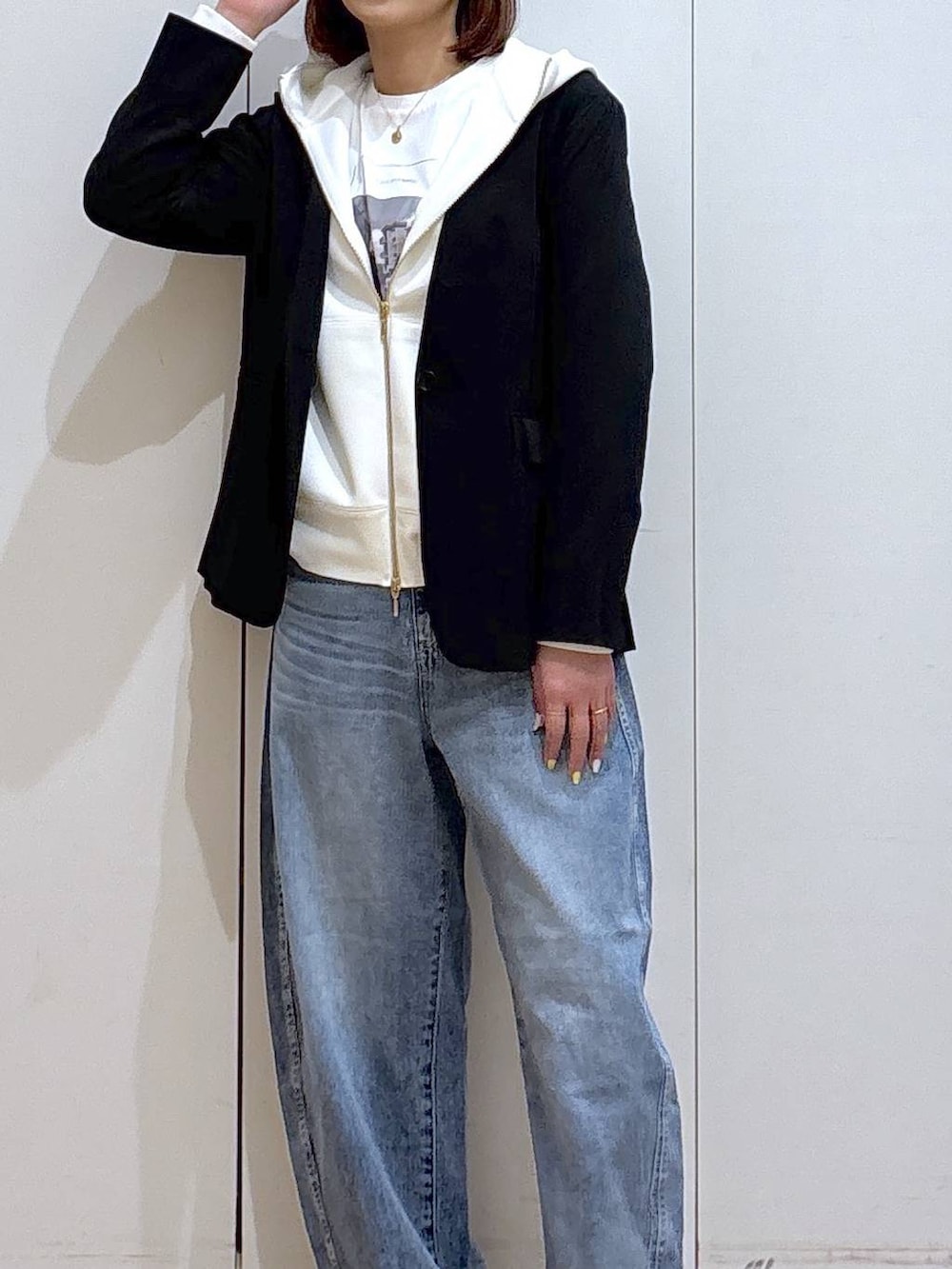 ホワイト系のパーカー、ブラック系のノーカラージャケット、ブルー系のデニムパンツを着用したレディースの春コーディネートの4枚目の写真