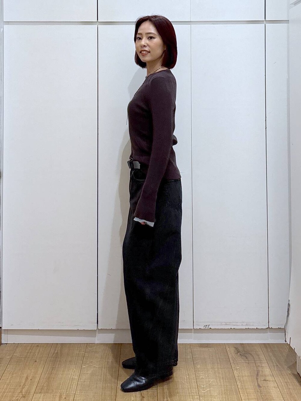 ブラック系のブーツ、ブラック系のデニムパンツ、ブラウン系のニット/セーターを着用したレディースの春コーディネートの3枚目の写真