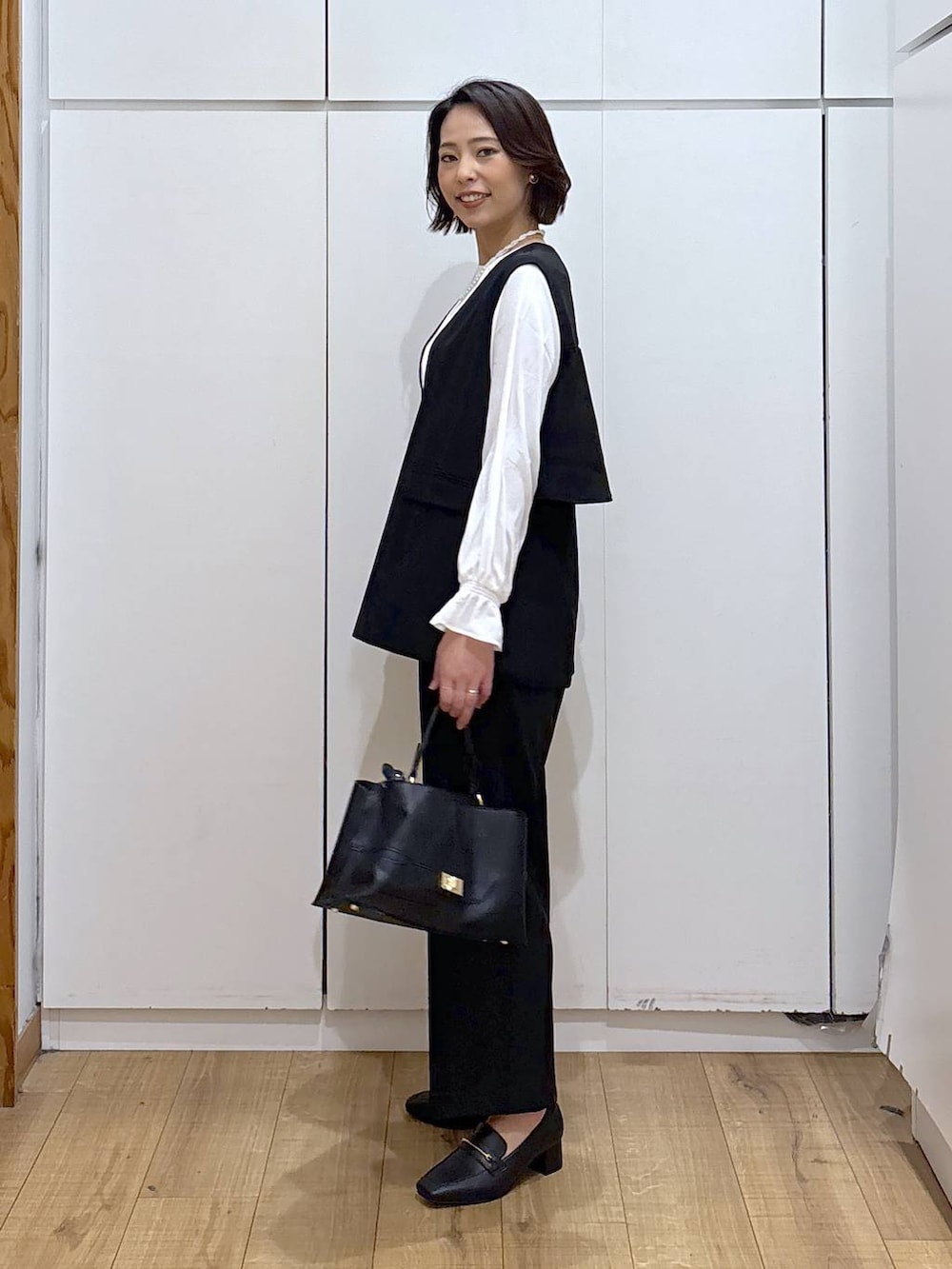 ブラック系のローファー、ブラック系のセットアップ、ブラック系のショルダーバッグを着用したレディースの冬コーディネートの5枚目の写真