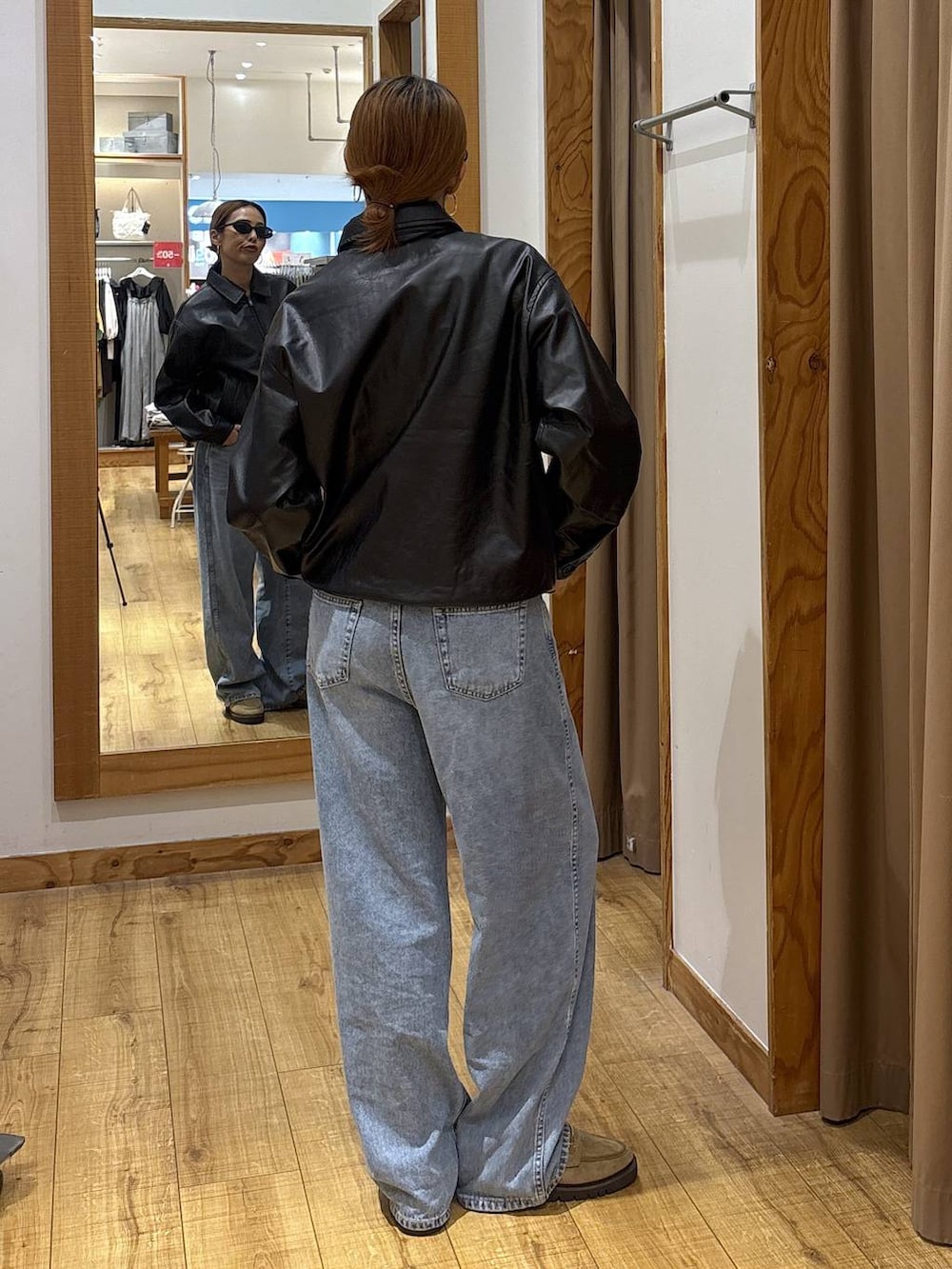 ブラック系のブルゾン、ブルー系のデニムパンツ、ベージュ系のローファーを着用したレディースの秋コーディネートの5枚目の写真