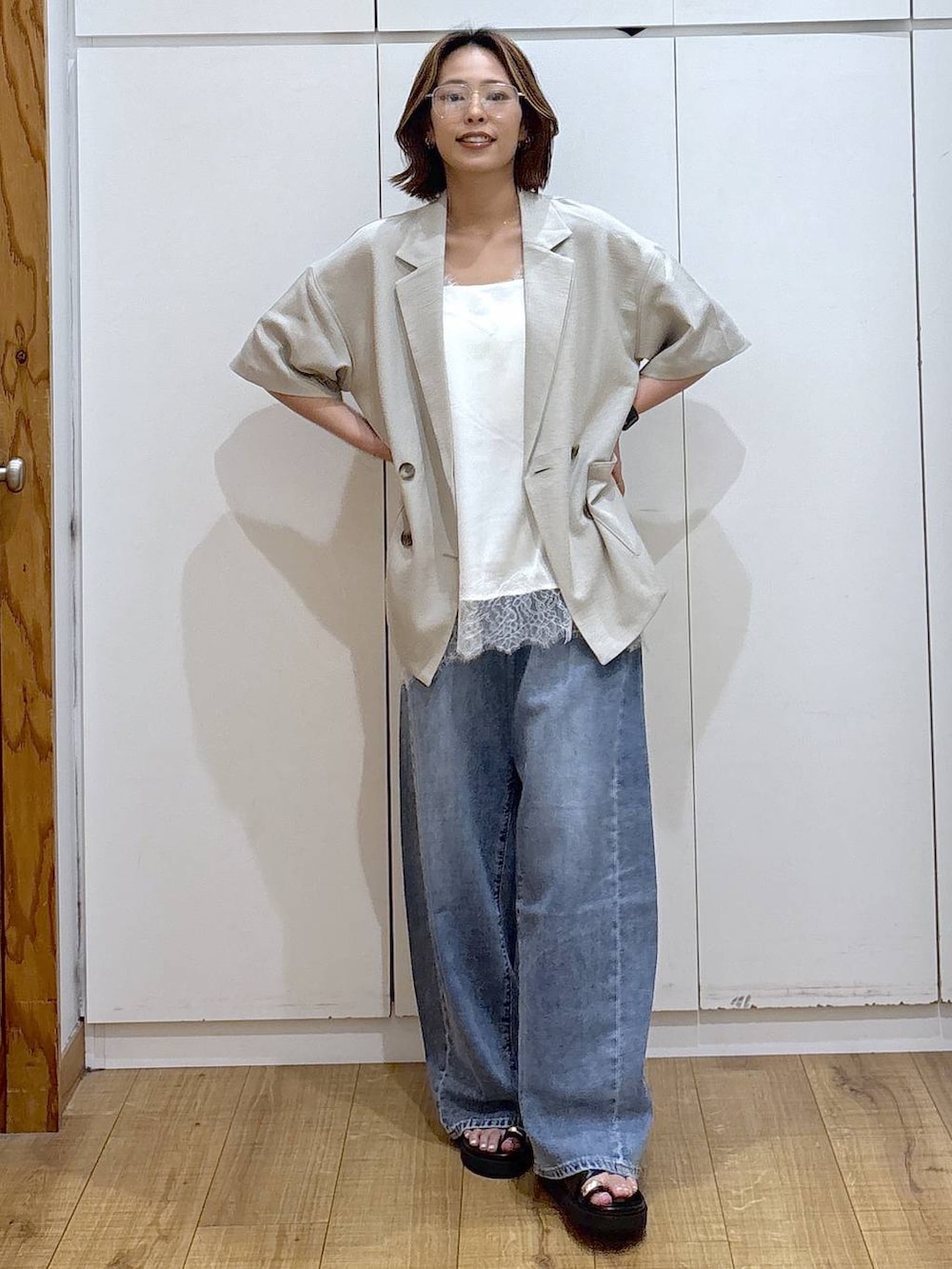 ホワイト系のキャミソール、ブルー系のデニムパンツ、ベージュ系のテーラードジャケットを着用したレディースの春コーディネートの3枚目の写真