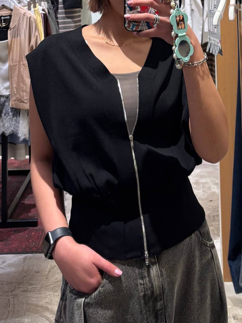 グレー系のデニムパンツ、ブラック系のベストを着用したレディースの春コーディネートの2枚目の写真