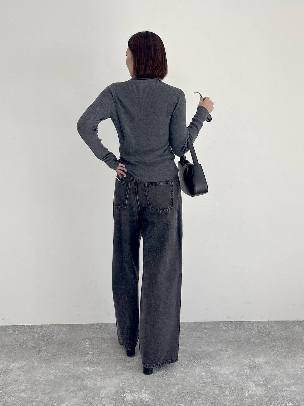 ブラック系のデニムパンツ、ブラック系のブーツ、グレー系のニット/セーターを着用したレディースの秋コーディネートの2枚目の写真