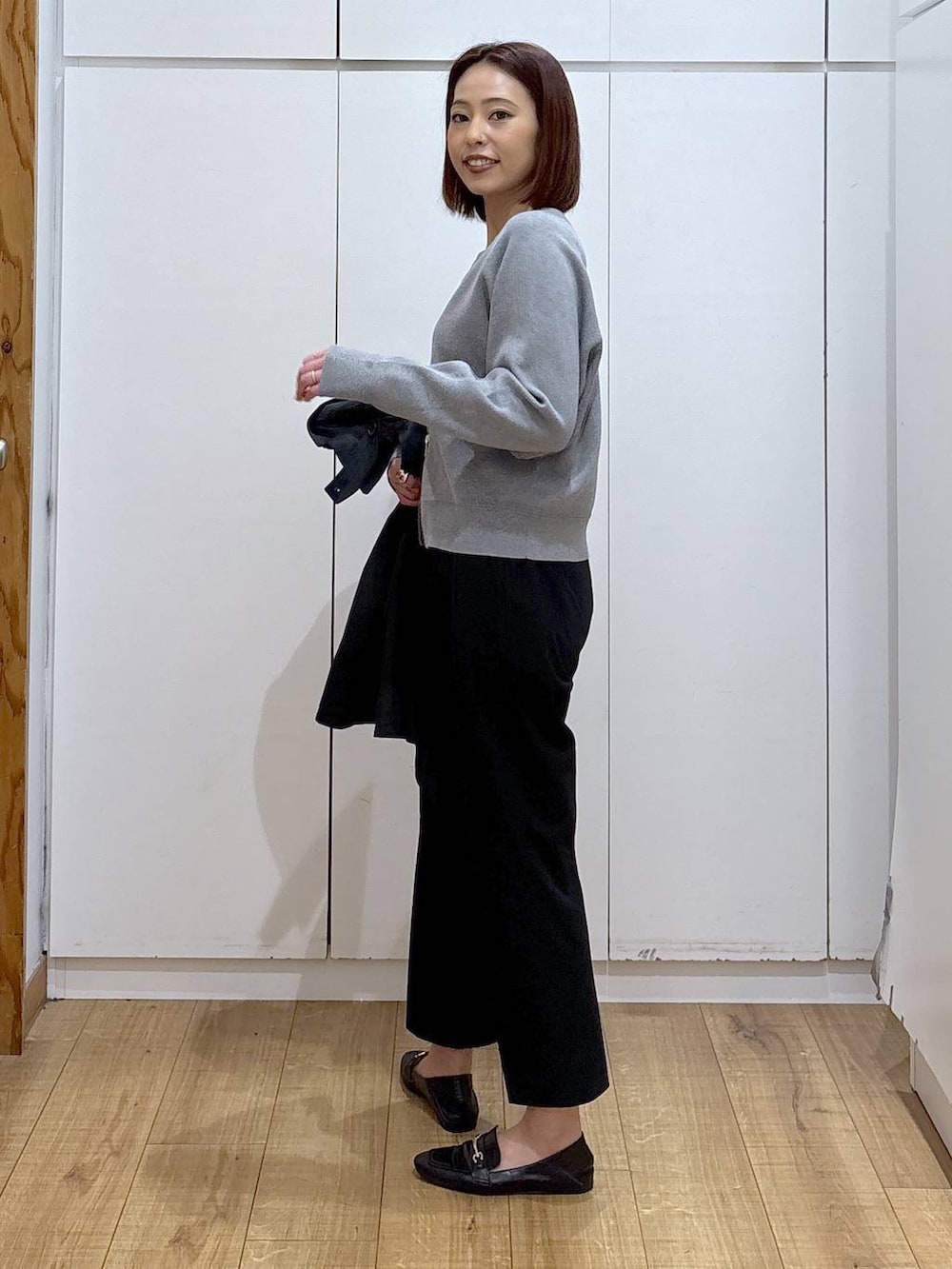 ブラック系のローファー、ブラック系のスラックス、ブルー系のトレンチコートを着用したレディースの春コーディネートの5枚目の写真