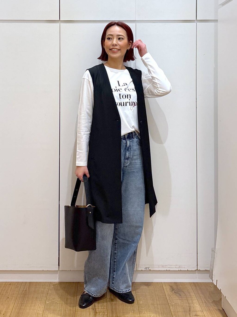 ブルー系のデニムパンツ、ブラック系のローファー、ブラック系のベストを着用したレディースの春コーディネートの2枚目の写真