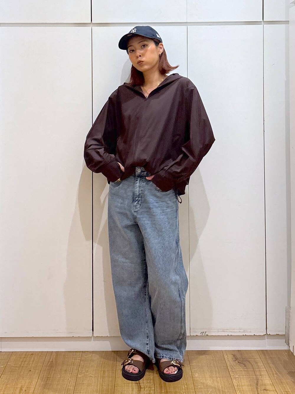 ブルー系のデニムパンツ、ブラウン系のマウンテンパーカー、ブルー系のキャップを着用したレディースの夏コーディネートの2枚目の写真