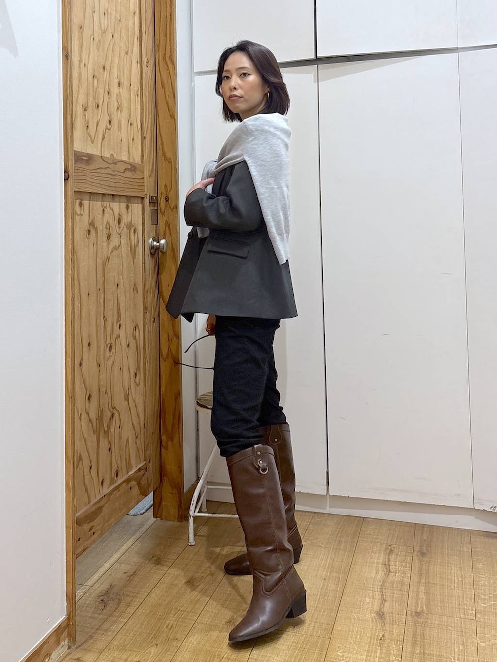 ブラック系のデニムパンツ、ブラウン系のブーツ、グレー系のニット/セーターを着用したレディースの秋コーディネートの4枚目の写真