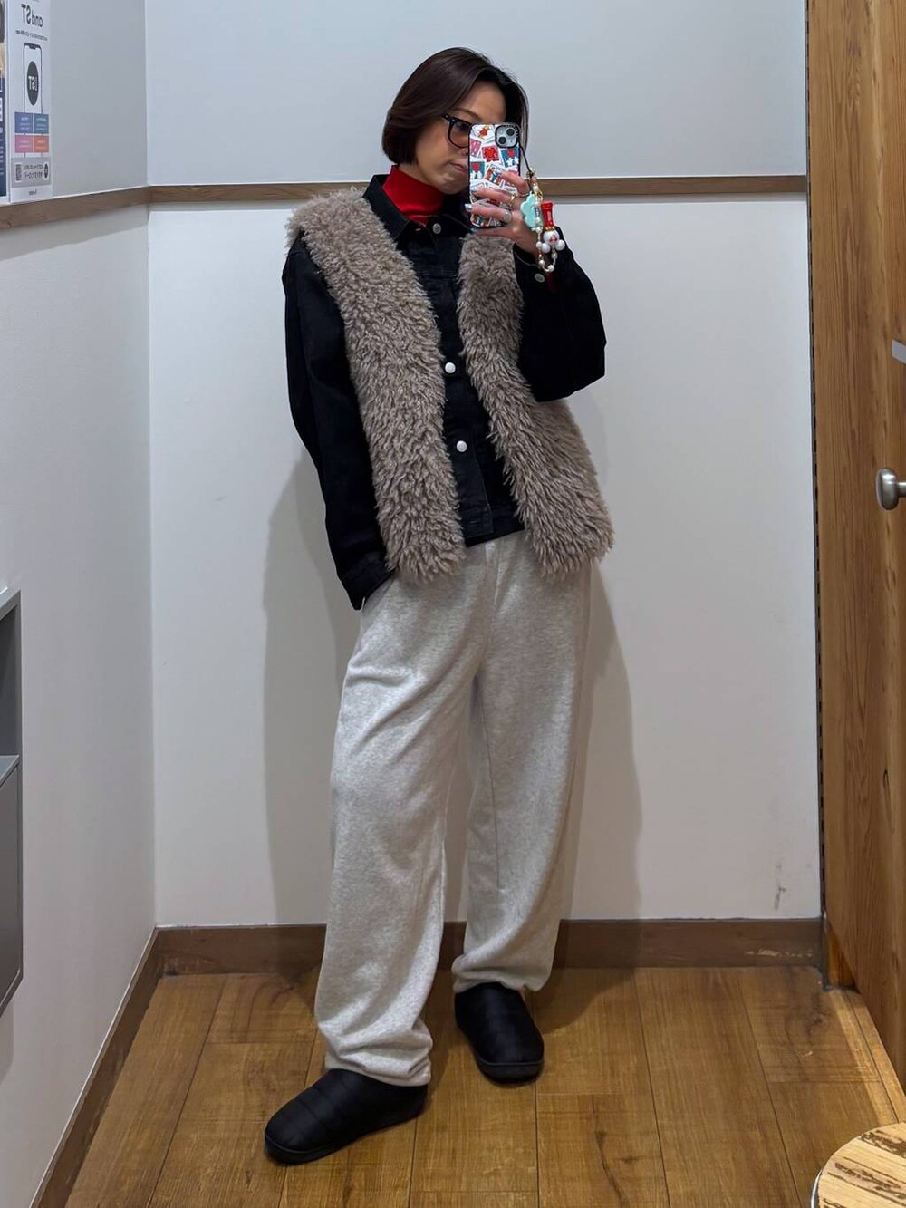 レッド系のニット/セーター、ブラック系のデニムジャケット、ゴールド系のピアス(両耳用)を着用したレディースの冬コーディネートの6枚目の写真