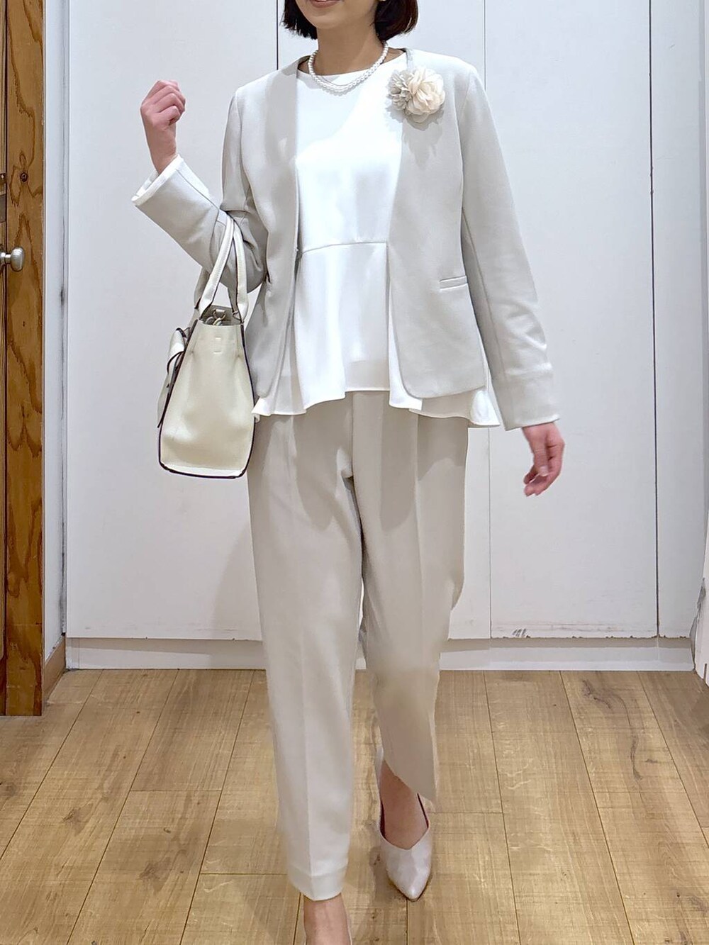 ホワイト系のパンプス、ベージュ系のセットアップ、ベージュ系のハンドバッグを着用したレディースの冬コーディネートの7枚目の写真