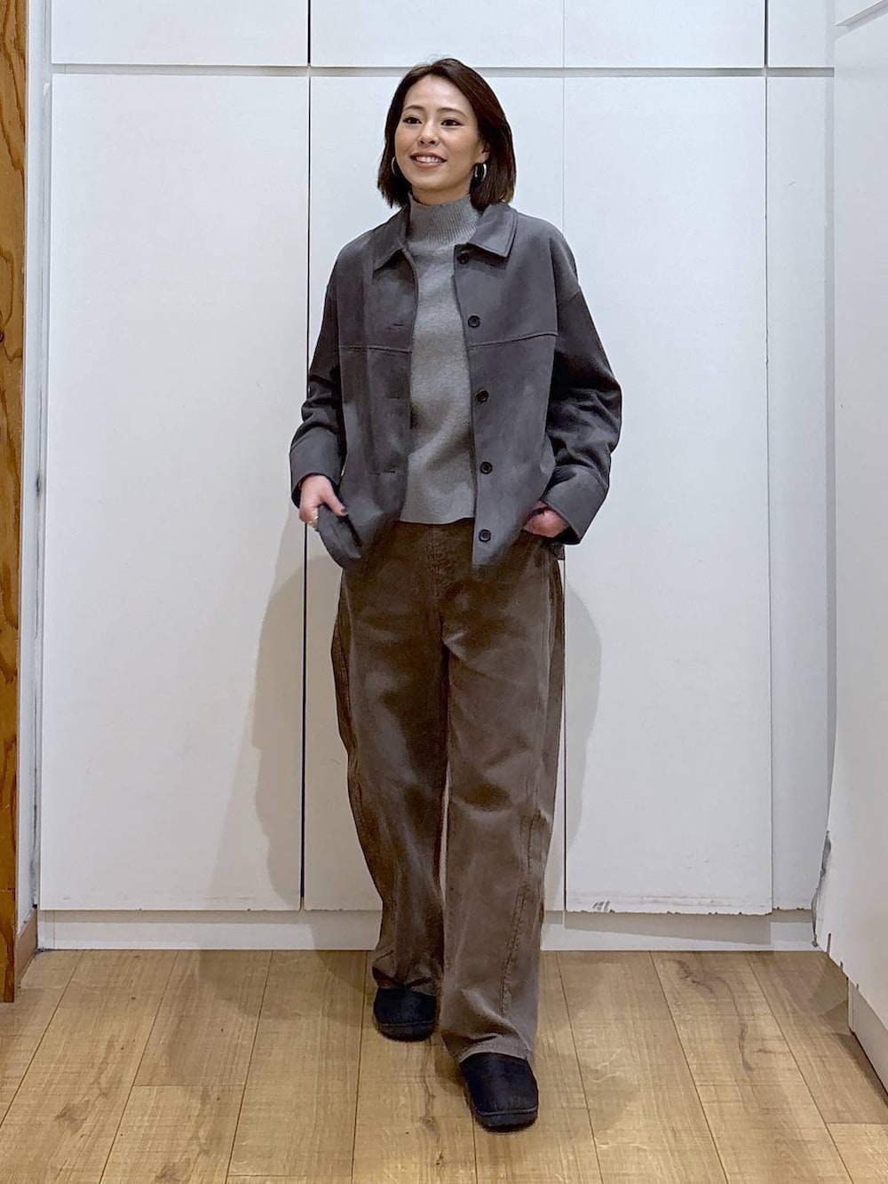 グレー系のニット/セーター、グレー系のテーラードジャケット、ブラウン系のデニムパンツを着用したレディースの冬コーディネートの2枚目の写真