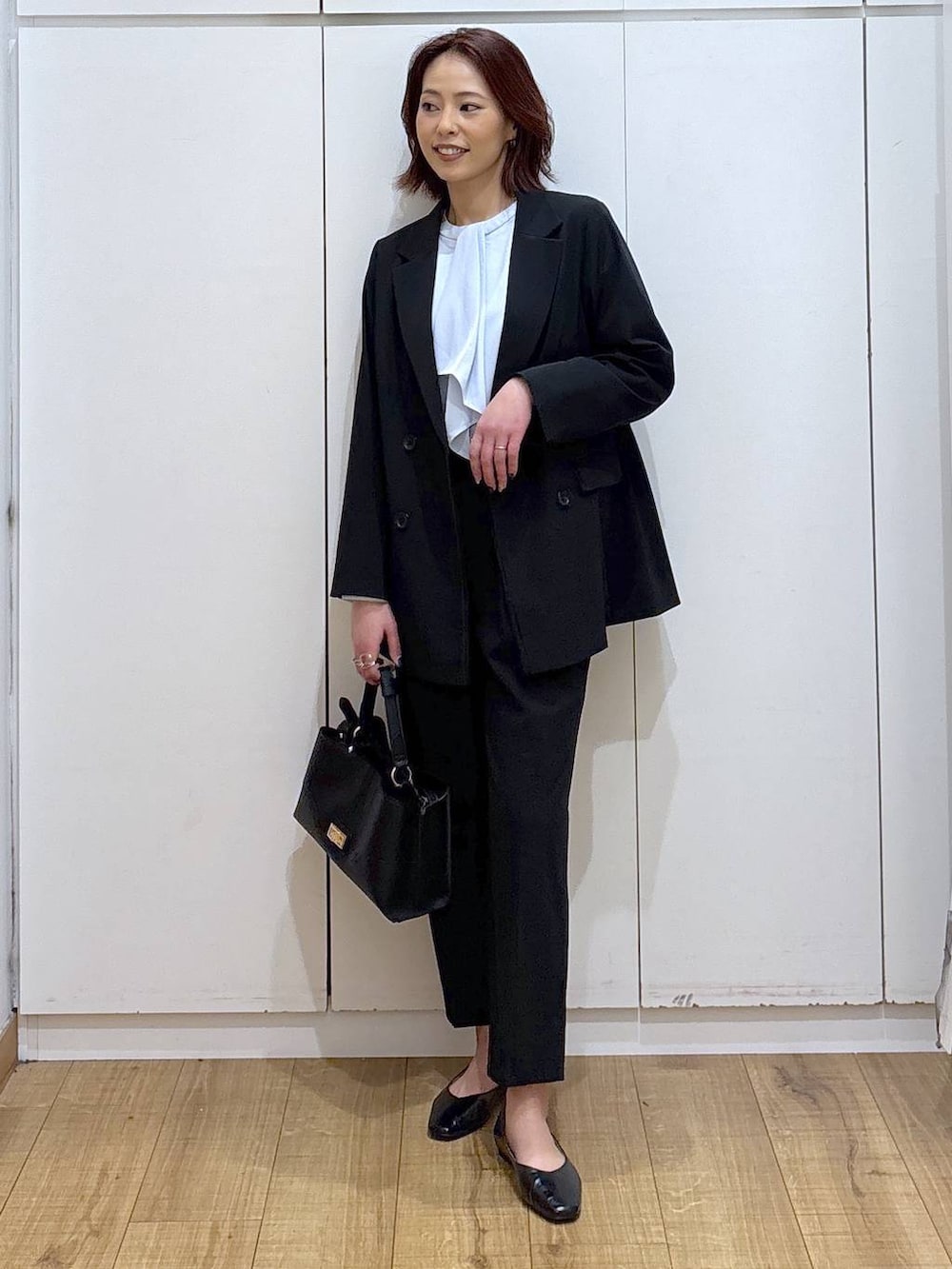 ブラック系のパンプス、ブラック系のスラックス、ブルー系のシャツ/ブラウスを着用したレディースの春コーディネートの2枚目の写真