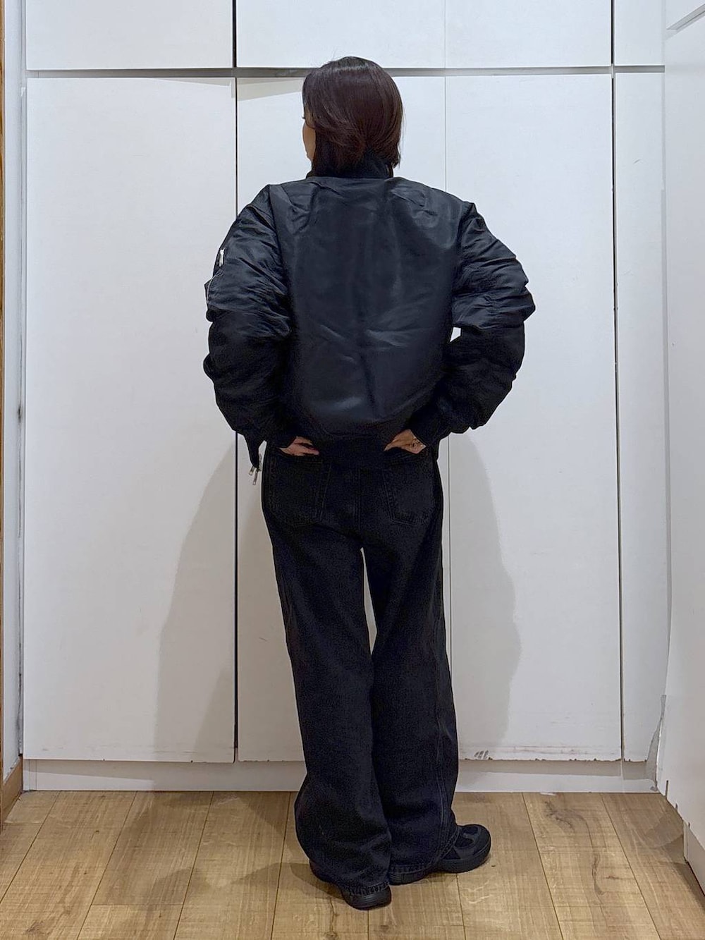 ブラック系のデニムパンツ、ブラック系のスニーカー、ホワイト系のTシャツ/カットソーを着用したレディースの秋コーディネートの4枚目の写真