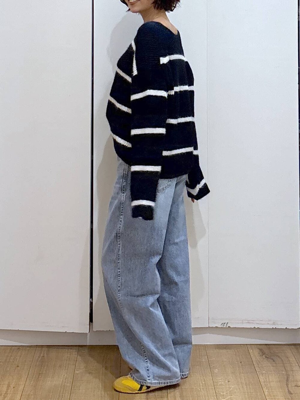 ブルー系のデニムパンツ、ブルー系のニット/セーター、ゴールド系のピアス(両耳用)を着用したレディースの冬コーディネートの6枚目の写真