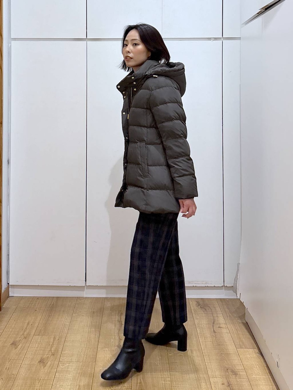 ブラウン系のダウンジャケット/コート、ブラック系のニット/セーター、ブルー系のその他パンツを着用したレディースの秋コーディネートの4枚目の写真