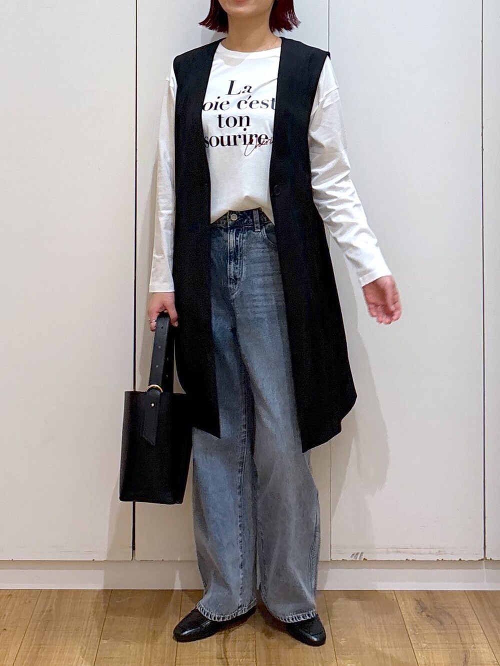 ブルー系のデニムパンツ、ブラック系のローファー、ブラック系のベストを着用したレディースの春コーディネートの5枚目の写真