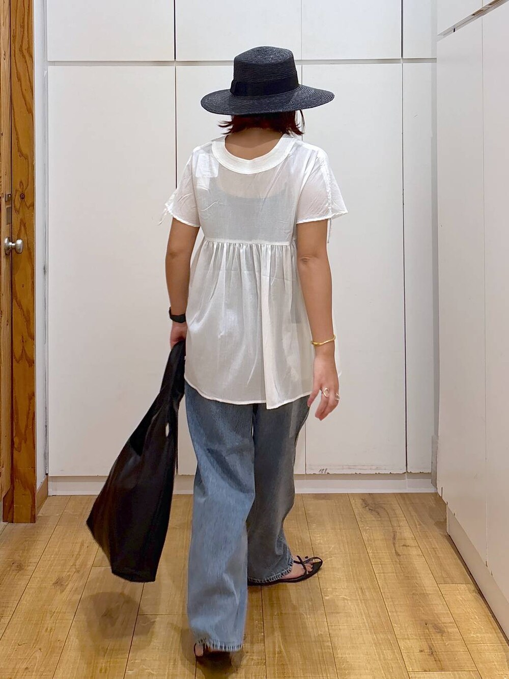 ブルー系のデニムパンツ、ブラック系のサンダル、ホワイト系のシャツ/ブラウスを着用したレディースの夏コーディネートの3枚目の写真