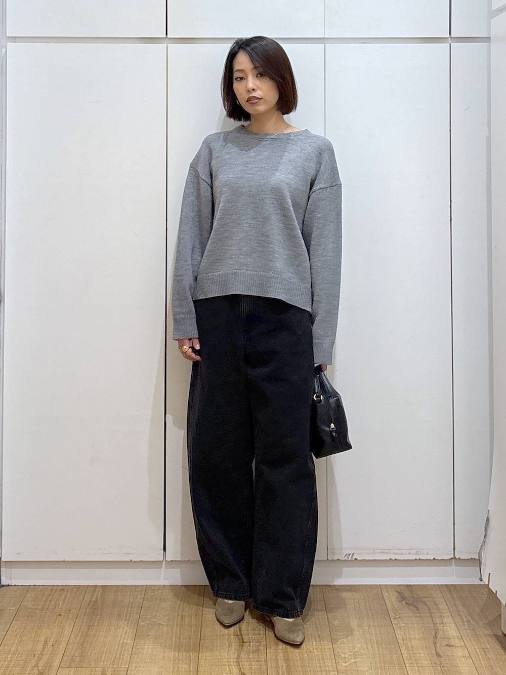 ブラック系のショルダーバッグ、ベージュ系のパンプス、ブラック系のデニムパンツを着用したレディースの冬コーディネートの3枚目の写真