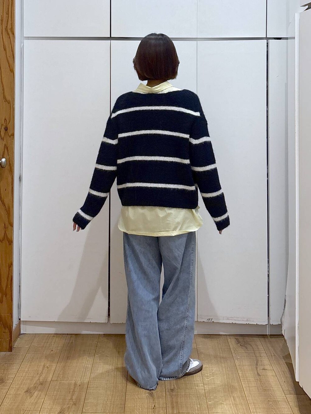 ブルー系のデニムパンツ、イエロー系のシャツ/ブラウス、ブルー系のニット/セーターを着用したレディースの冬コーディネートの4枚目の写真