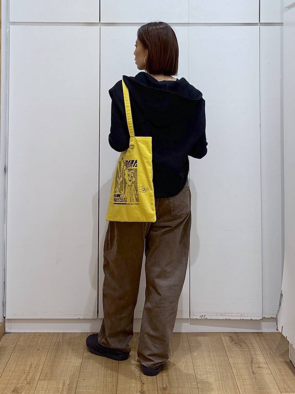 ブラウン系のデニムパンツ、イエロー系のトートバッグ、ブラック系のTシャツ/カットソーを着用したレディースの冬コーディネートの6枚目の写真