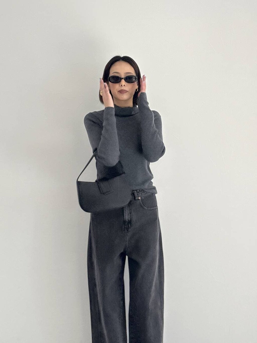 ブラック系のデニムパンツ、ブラック系のブーツ、グレー系のニット/セーターを着用したレディースの秋コーディネートの7枚目の写真