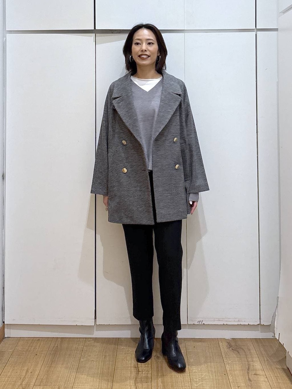 グレー系のチェスターコート、ブラック系のその他パンツ、グレー系のニット/セーターを着用したレディースの秋コーディネートの3枚目の写真