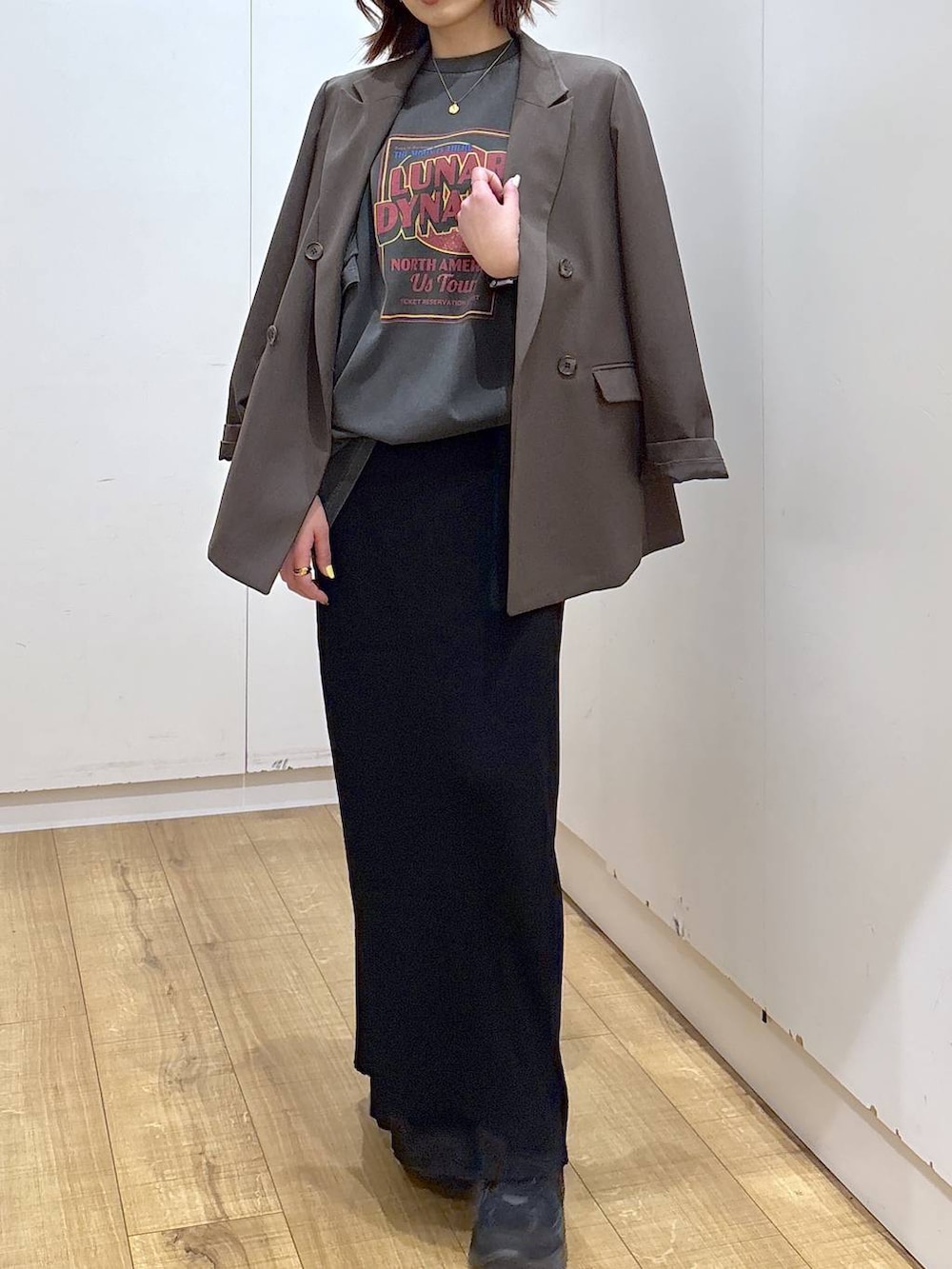 ブラウン系のテーラードジャケット、ブラック系のスカート、ゴールド系のネックレスを着用したレディースの春コーディネートの2枚目の写真