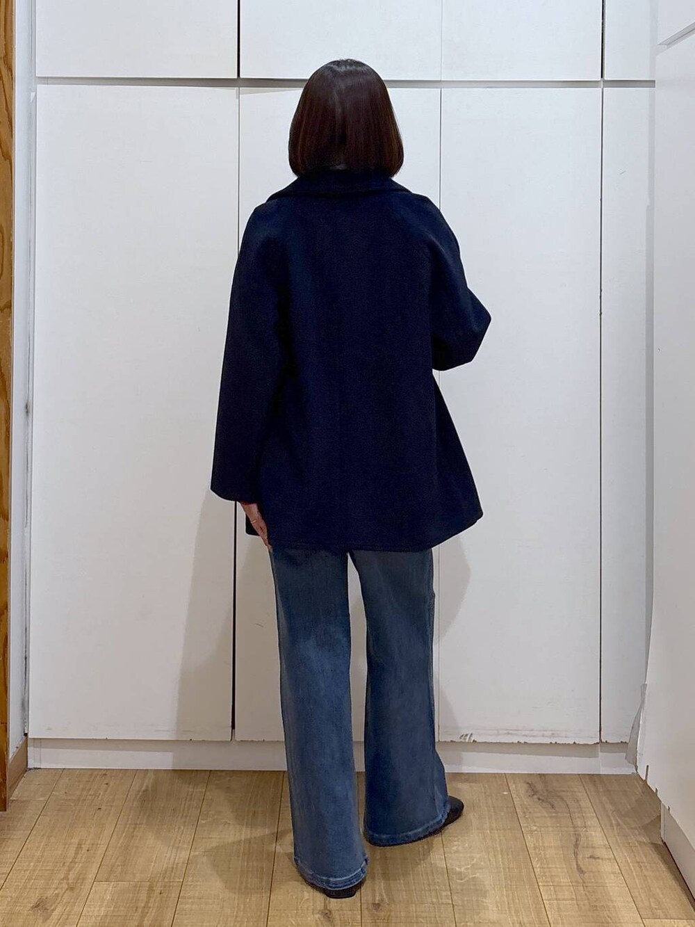 ブルー系のチェスターコート、ブラック系のブーツ、ブルー系のデニムパンツを着用したレディースの秋コーディネートの4枚目の写真