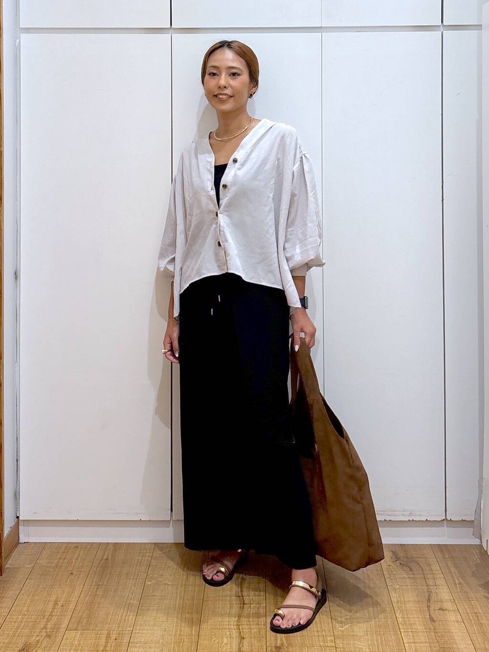 ブラック系のキャミソール、ブラウン系のサンダル、ブラック系のスカートを着用したレディースの秋コーディネートの2枚目の写真