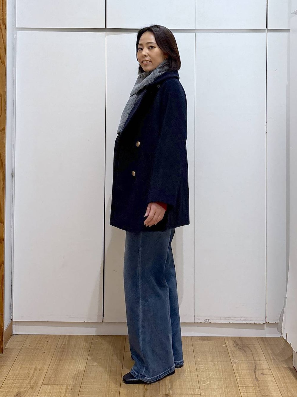 ブルー系のチェスターコート、ブラック系のブーツ、ブルー系のデニムパンツを着用したレディースの秋コーディネートの3枚目の写真