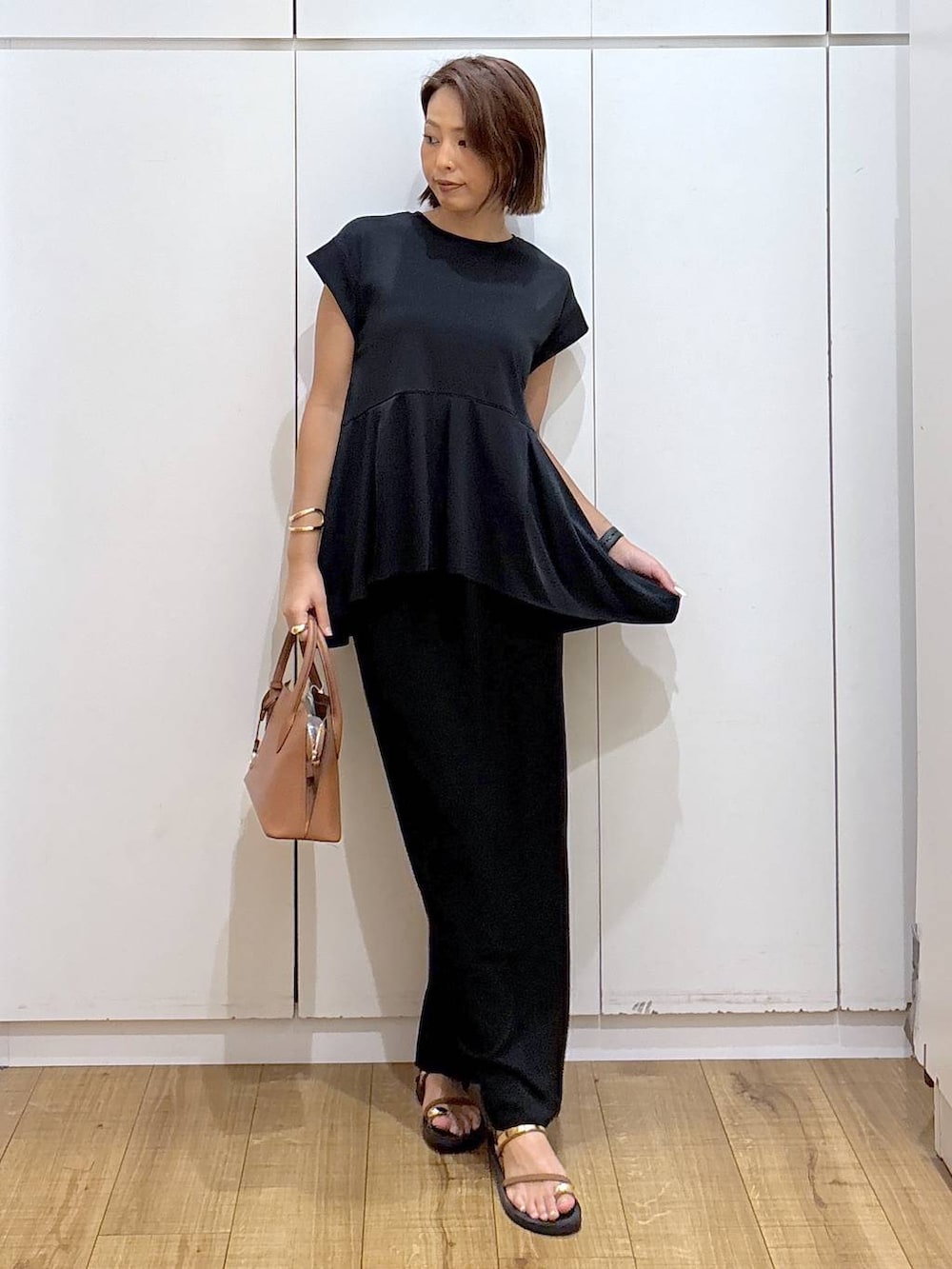 ブラック系のスカート、ブラウン系のショルダーバッグ、ブラック系のTシャツ/カットソーを着用したレディースの夏コーディネートの5枚目の写真