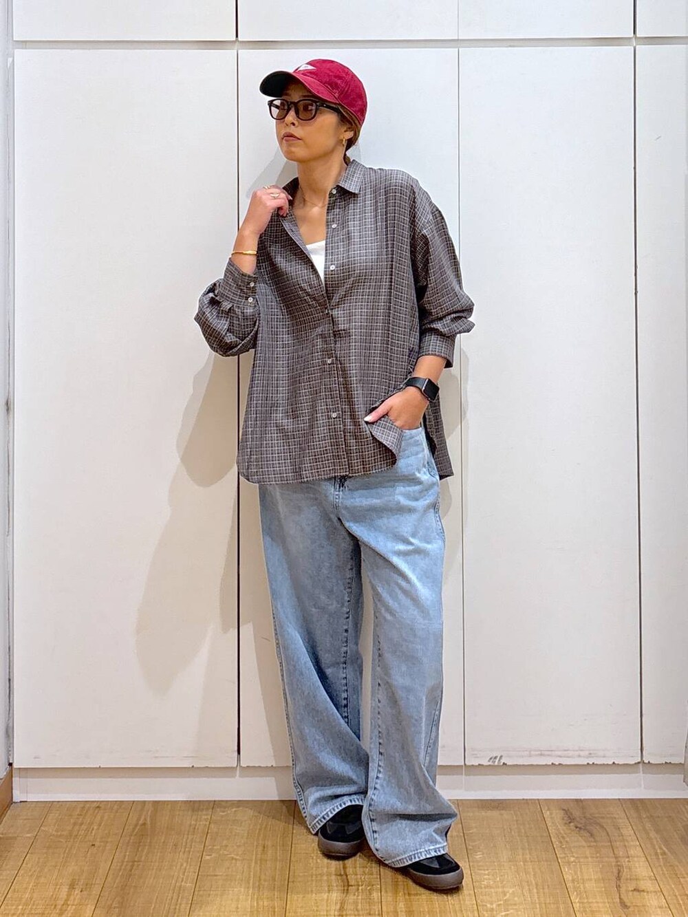 ブラック系のスニーカー、ホワイト系のキャミソール、ブルー系のデニムパンツを着用したレディースの秋コーディネートの2枚目の写真