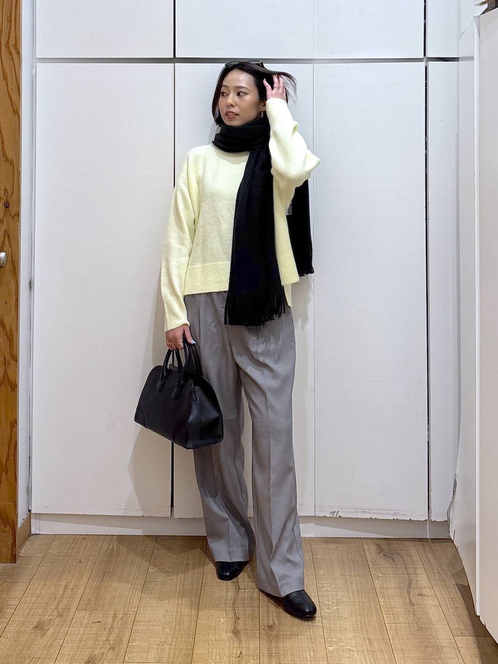 イエロー系のニット/セーター、グレー系のその他パンツ、ブラック系のショルダーバッグを着用したレディースの冬コーディネートの4枚目の写真