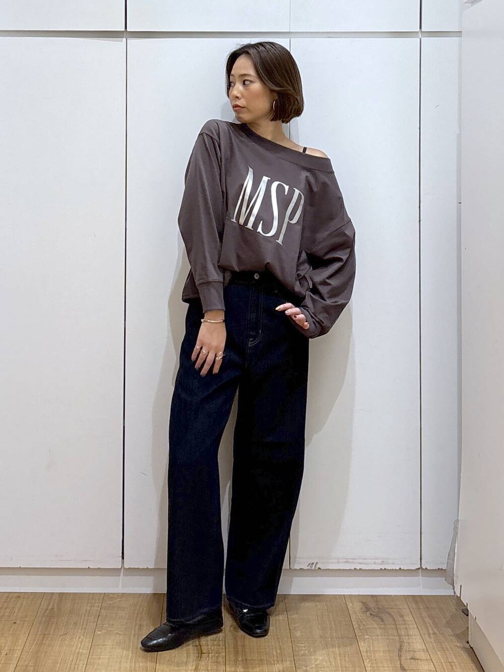 ブラック系のローファー、ブルー系のデニムパンツ、ブラウン系のスウェットを着用したレディースの秋コーディネートの2枚目の写真