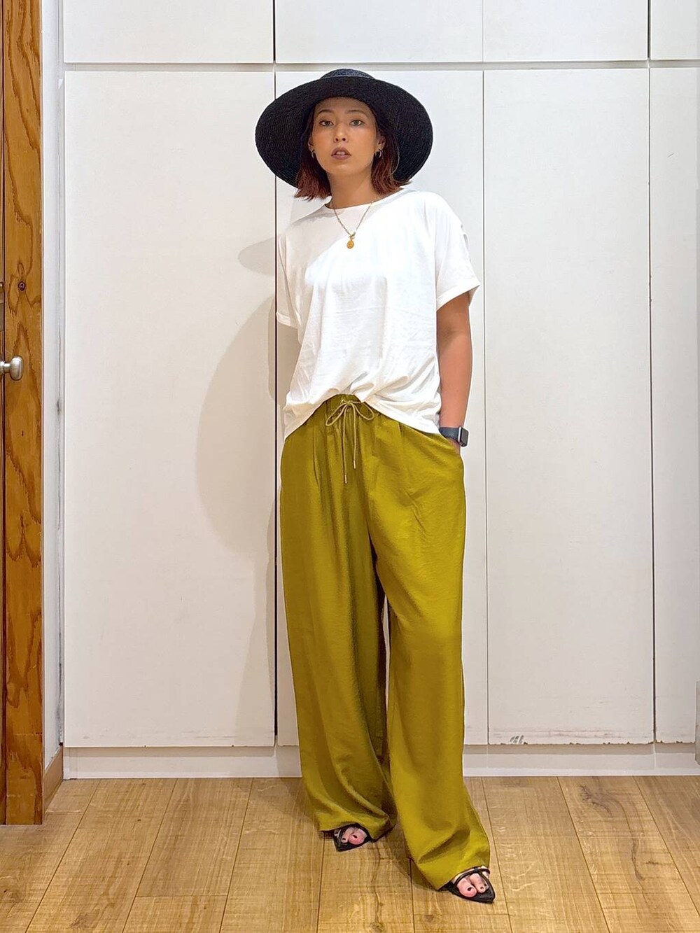 ブラック系のサンダル、イエロー系のその他パンツ、ホワイト系のTシャツ/カットソーを着用したレディースの夏コーディネートの2枚目の写真