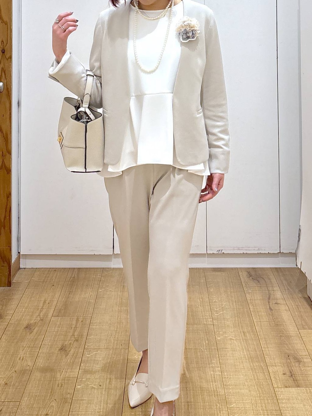ベージュ系のセットアップ、ベージュ系のショルダーバッグ、ホワイト系のローファーを着用したレディースの春コーディネートの6枚目の写真