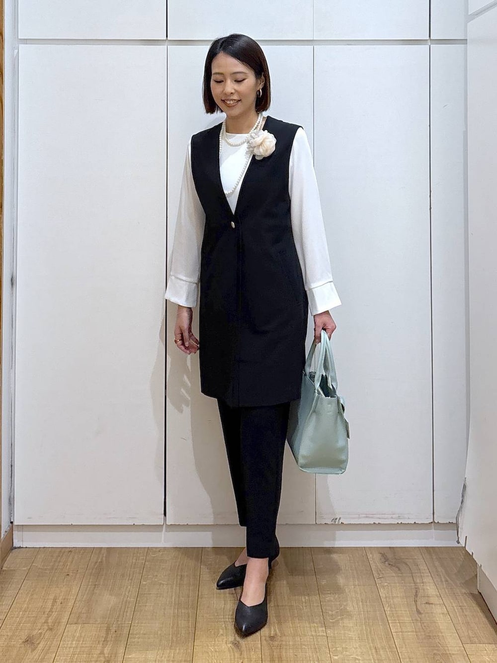 ブラック系のパンプス、ブラック系のスラックス、ブラック系のセットアップを着用したレディースの冬コーディネートの6枚目の写真