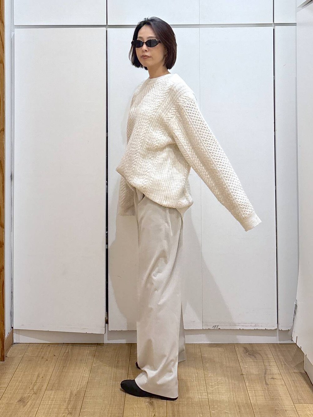 ベージュ系のスラックス、ブラック系のブーツ、ホワイト系のニット/セーターを着用したレディースの冬コーディネートの4枚目の写真