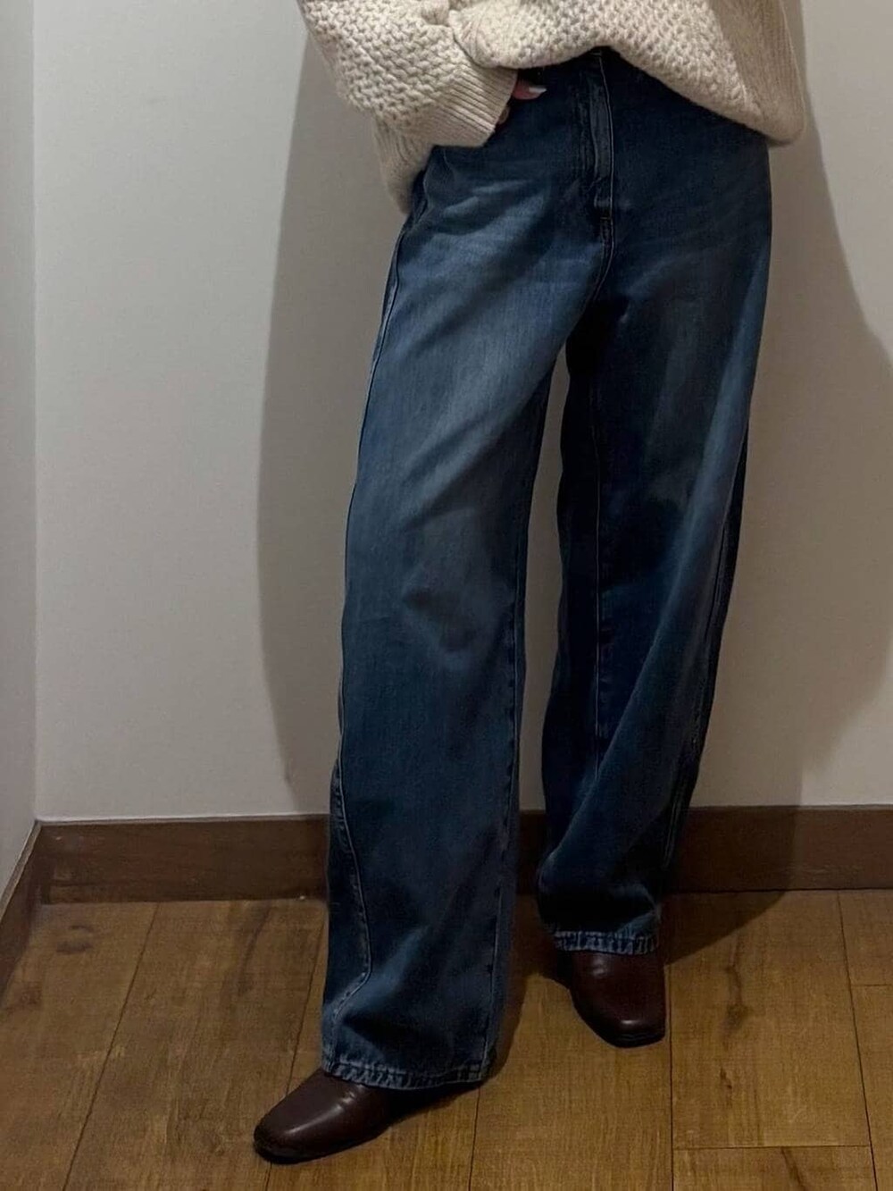 ブラウン系のブーツ、ホワイト系のニット/セーター、ブルー系のデニムパンツを着用したレディースの冬コーディネートの3枚目の写真