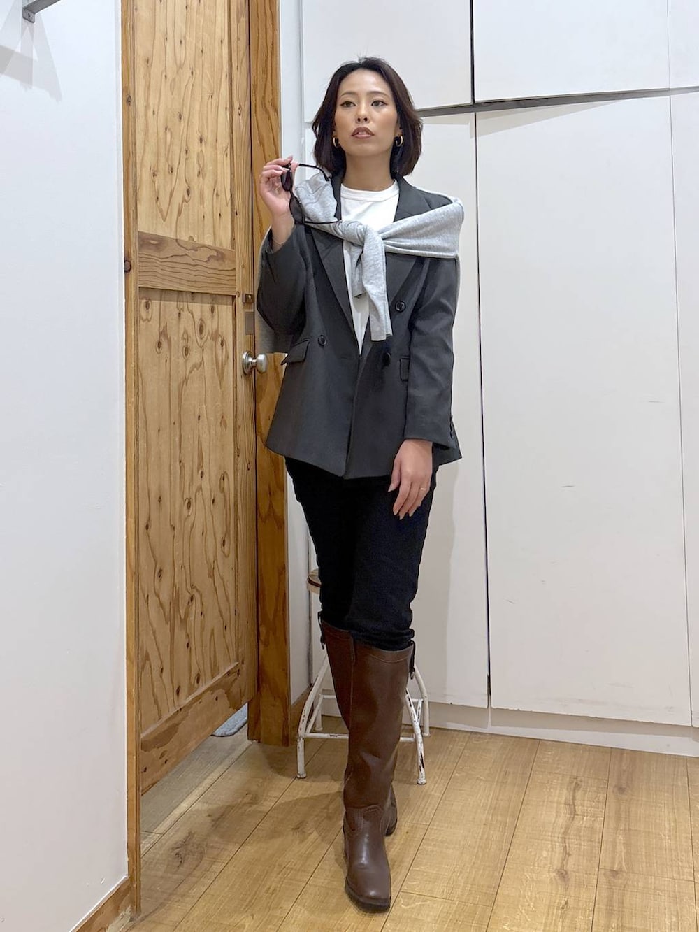 ブラック系のデニムパンツ、ブラウン系のブーツ、グレー系のニット/セーターを着用したレディースの秋コーディネートの2枚目の写真