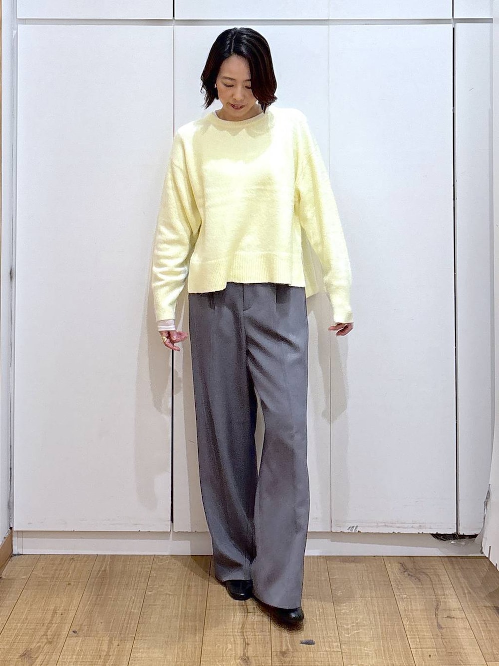 イエロー系のニット/セーター、ブラック系のブーツ、ゴールド系のピアス（両耳用）を着用したレディースの冬コーディネートの4枚目の写真