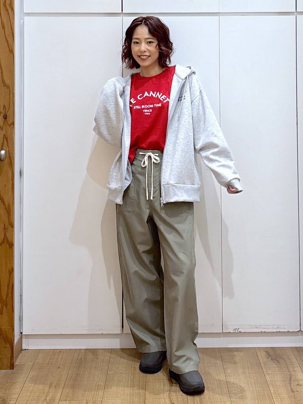 レッド系のTシャツ/カットソー、グリーン系のその他パンツ、グレー系のパーカーを着用したレディースの春コーディネートの2枚目の写真