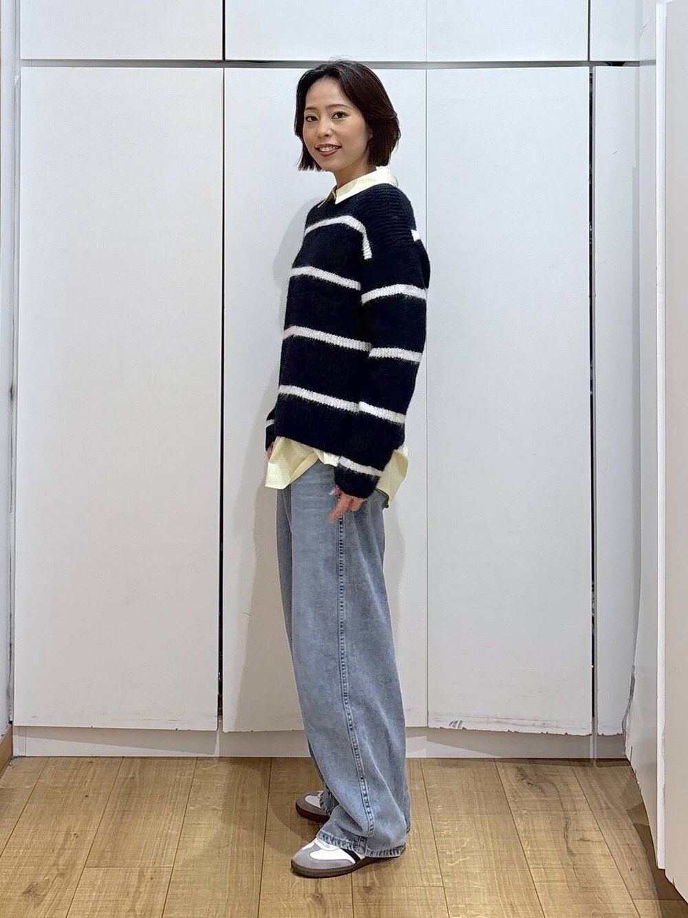 ブルー系のデニムパンツ、イエロー系のシャツ/ブラウス、ブルー系のニット/セーターを着用したレディースの冬コーディネートの3枚目の写真