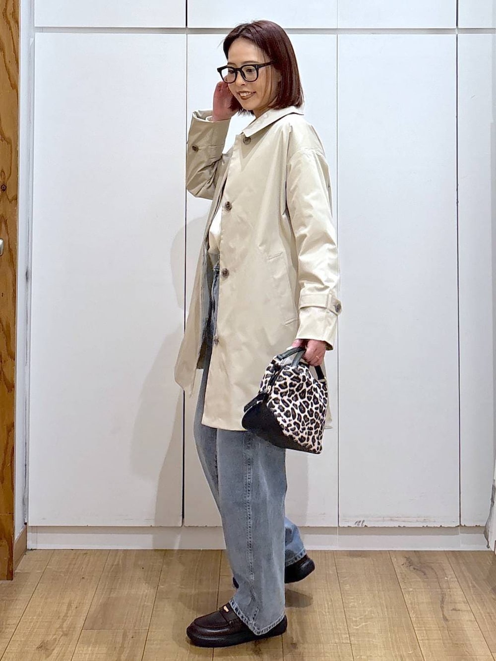 その他のショルダーバッグ、ブルー系のデニムパンツ、ベージュ系のステンカラーコートを着用したレディースの春コーディネートの3枚目の写真