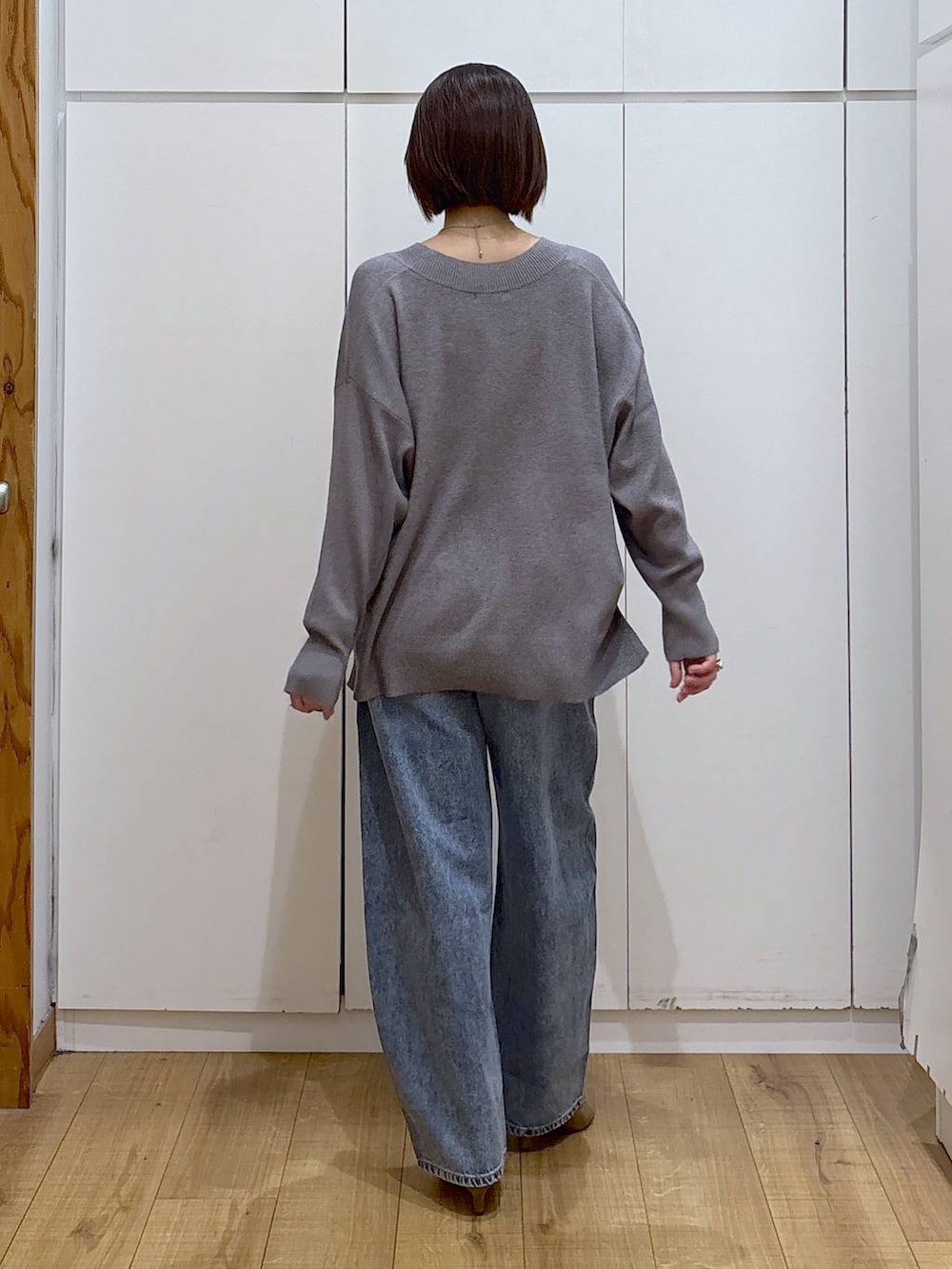 グレー系のニット/セーター、ベージュ系のブーツ、ブルー系のデニムパンツを着用したレディースの冬コーディネートの5枚目の写真