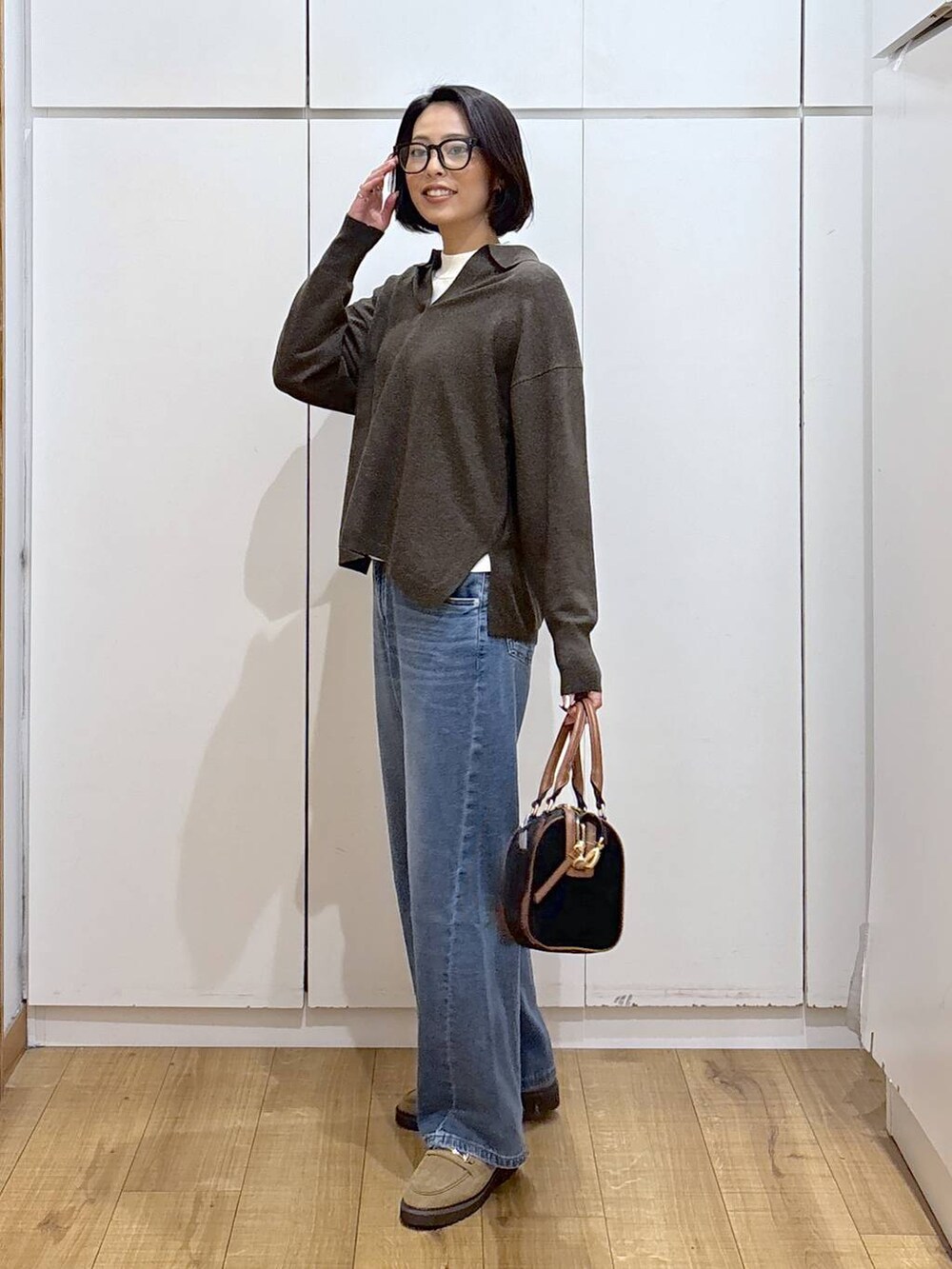 ホワイト系のニット/セーター、ベージュ系のローファー、ブルー系のデニムパンツを着用したレディースの秋コーディネートの4枚目の写真