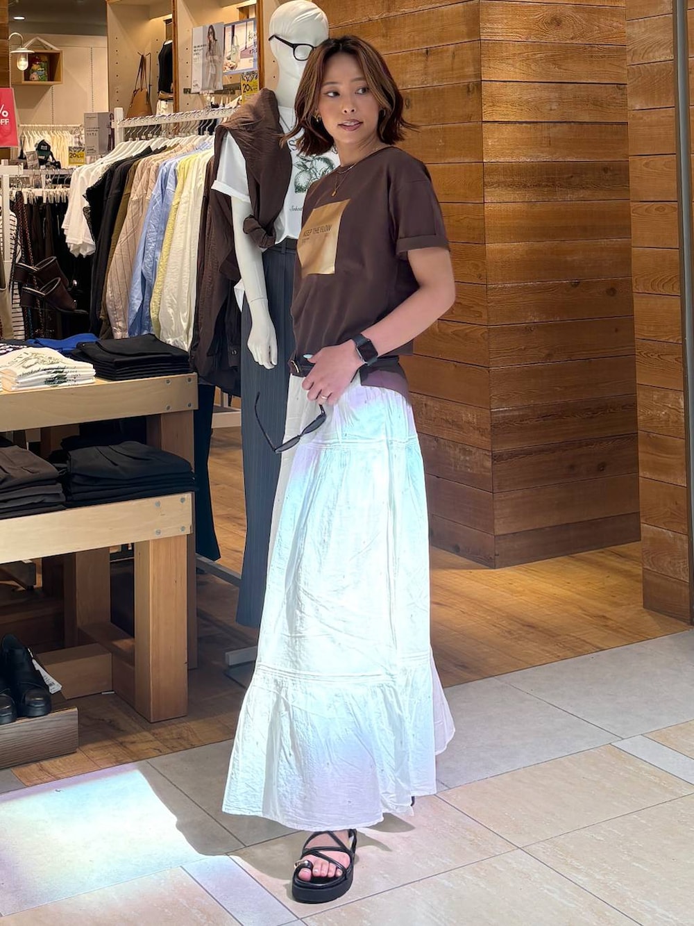 ホワイト系のスカート、ブラウン系のTシャツ/カットソー、ブラック系のサンダルを着用したレディースの春コーディネートの4枚目の写真