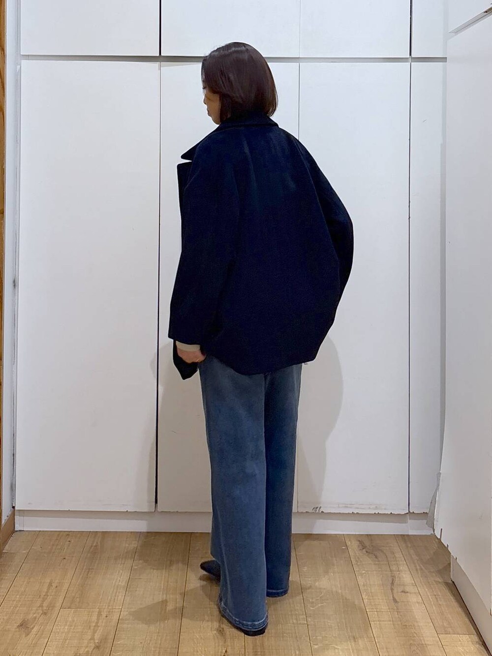 ブルー系のチェスターコート、ベージュ系のスウェット、ブラック系のブーツを着用したレディースの秋コーディネートの4枚目の写真