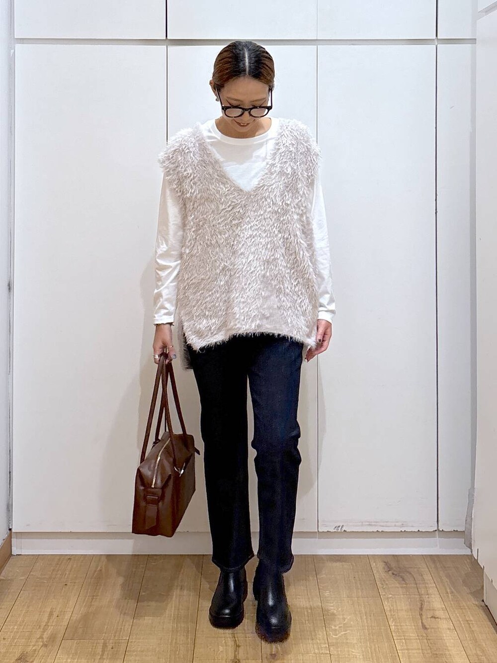 ブラウン系のボストンバッグ、ブルー系のデニムパンツ、ホワイト系のTシャツ/カットソーを着用したレディースの秋コーディネートの4枚目の写真