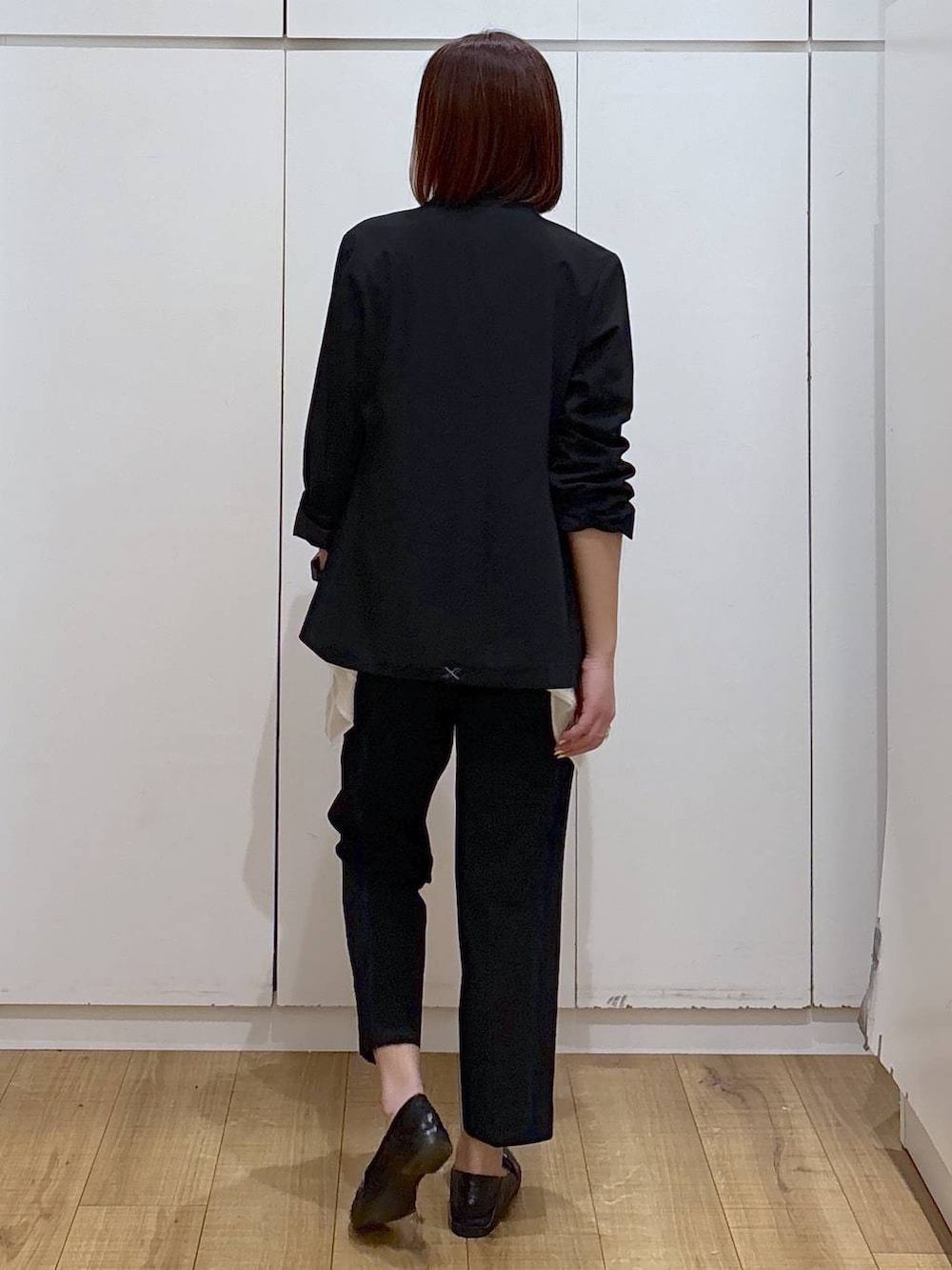 ブラック系のローファー、ブラック系のスラックス、ブラック系のノーカラージャケットを着用したレディースの春コーディネートの4枚目の写真